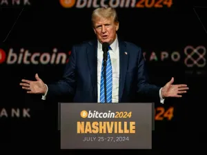 Donald Trump gesturing behind a lectern emblazoned with a Bitcoin conference logo