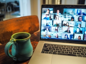 a mug next to a laptop that shows a virtual meeting