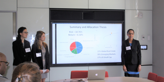 Three female students giving a presentation in front of a PowerPoint slide